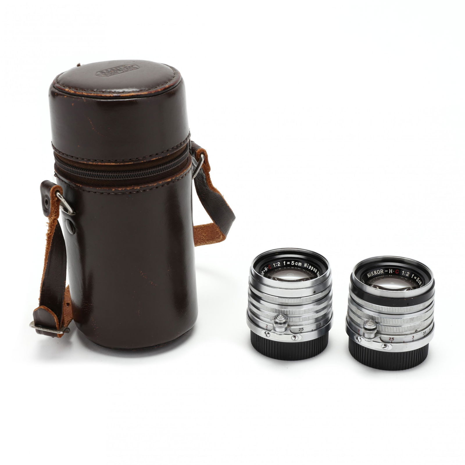 Pair of Nikkor Kogaku H.C 5cm 50mm f/2 Lenses: Pair of Nikkor Kogaku H.C 5cm 50mm f/2 LensesJapan, Nikon, No.'s 721865 and 746809; includes lens caps and a #12 leather Leica lens carrying case with strap. 2 in. (lens) Private Collection of a Gentl