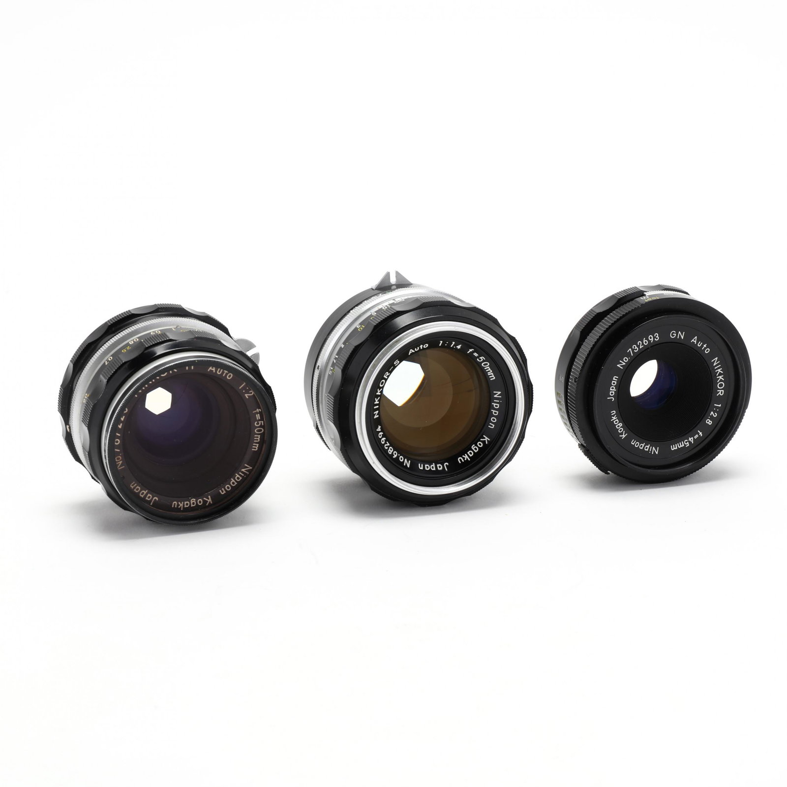 Three Nikkor Nippon Kogaku Camera Lenses: Three Nikkor Nippon Kogaku Camera Lenses to include: Nikkor-S Auto 1:1.4 f=50mm lens, No. 682994; Nikkor-H Auto 1:2 f=50mm lens, No. 787220; NIkkor 1:2.8 f=45mm lens, No. 732693. Private Collection of