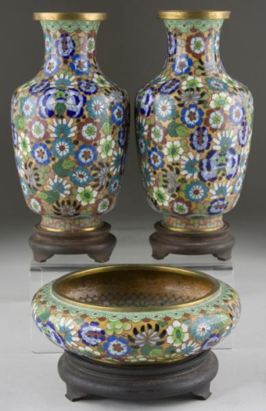 Cloisonne Garniture Set, circa 1900: Cloisonne Garniture Set, circa 1900 three pieces comprising a pair of baluster form vases and a low bowl, each with a matching wooden stand, allover millefleur design set against a speckled golden gro