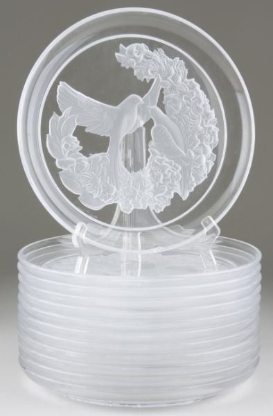 Set of (12) Lalique Tableware Plates: Set of (12) Lalique Tableware Plates clear and frosted crystal having a design of two birds perched upon a floral swag, etched signature "Lalique France." 10.5 in. One plate with chip. Collection of a