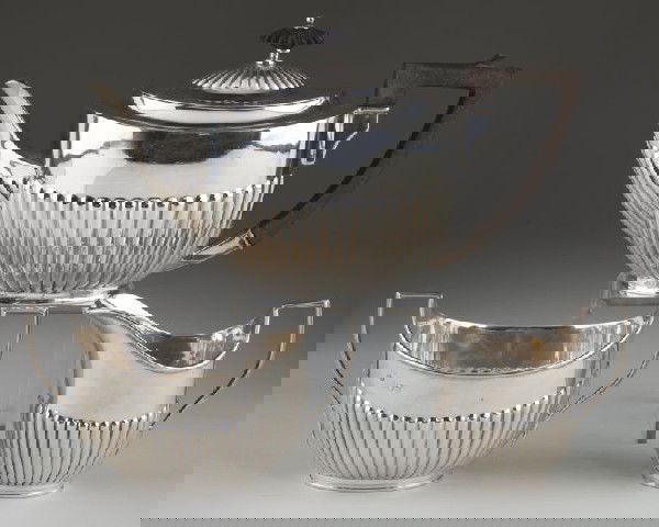 Edwardian Sterling Silver Tea Set: Edwardian Sterling Silver Tea Set three piece set including teapot (5 in.), open sugar, and cream jug; each with lobed decoration to lower body, each bearing the sponsor's mark of William Hutton & Son