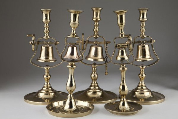 Group of Five Brass Tavern Candlesticks: Group of Five Brass Tavern Candlesticks three with wheel & bell in turned standard (one with floral engraving to bell); the remaining two with bell only (one with wide tray foot and copper bell). 11.5