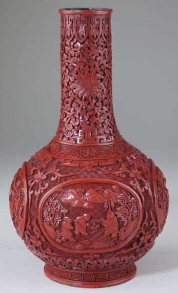 Carved Cinnabar Bottle Vase: Carved Cinnabar Bottle Vase 19th century, red lacquer, a tall peony carved neck sits above a bulbous body, each side hosting a medallion showing with workers amid a mountainous landscape, the whole su