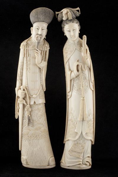 Pair of Antique Chinese Carved Ivory Tusk Figures: Pair of Antique Chinese Carved Ivory Tusk Figures representing an emperor and empress. The Emperor is armed with a ceremonial sword; the Empress sports an elaborate coiffure and her robes are carved w