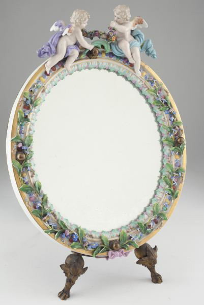 Meissen Figural Table Top Mirror: Meissen Figural Table Top Mirror late 19th-early 20th century, oval porcelain form highlighted by cherubs set within a gilt metal frame raised on two lion form front feet with "S" scroll, adjustable t