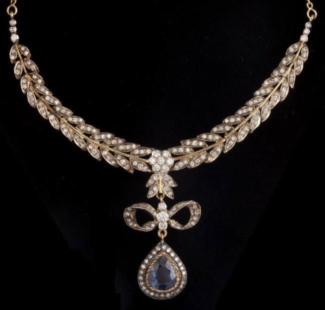 Sapphire and Diamond Bow Necklace: Sapphire and Diamond Bow Necklace set with 204 round single and full cut diamonds and one sapphire, the center part of the necklace designed as a line of leaves which moves towards a center diamond cl