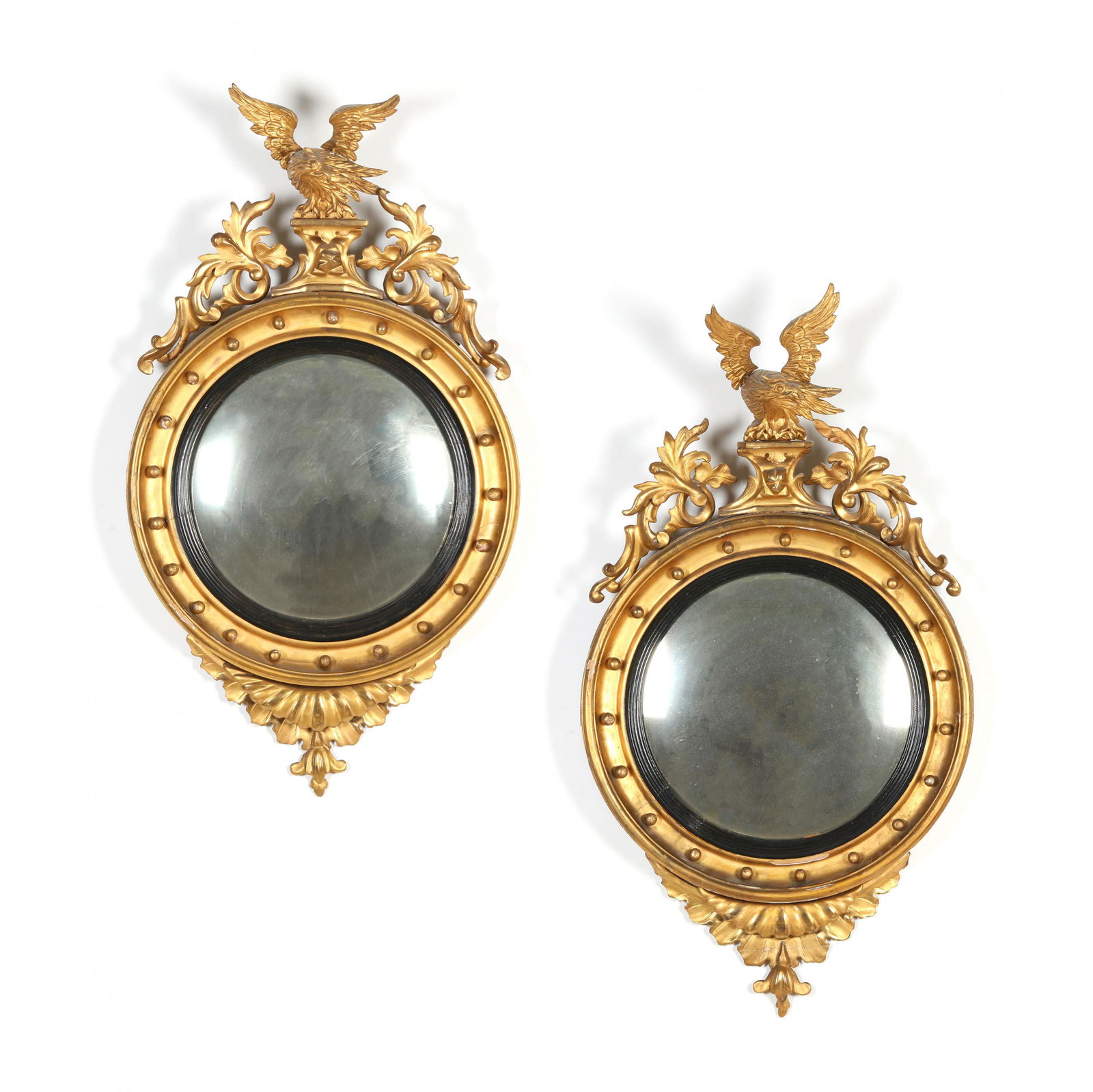 A Pair of Regency Carved Giltwood Convex Mirrors: A Pair of Regency Carved Giltwood Convex Mirrorscirca 1820, circular convex mirror plate within an ebonized reeded slip, surrounded by a gesso and gilt cove molded frame with spherical mount decoratio