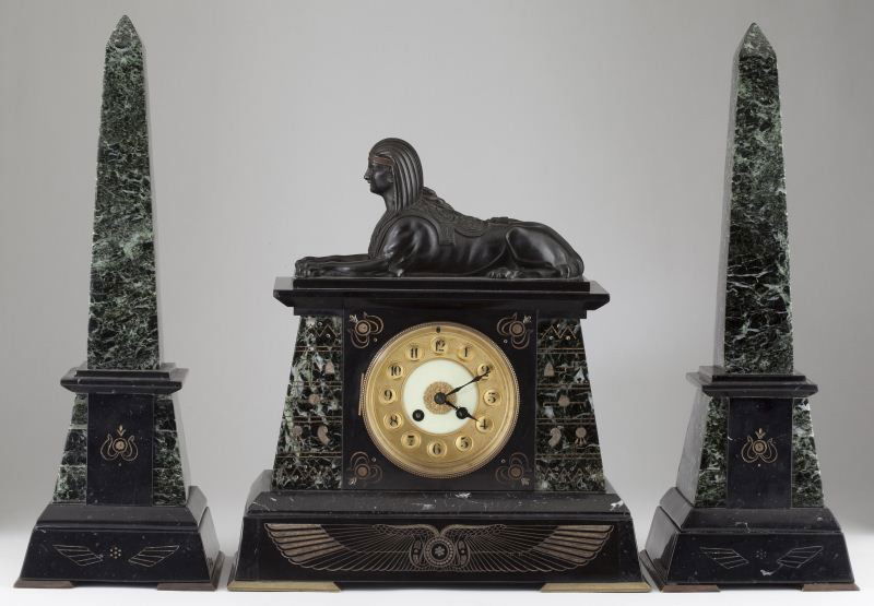 French Egyptian Revival Mantel Clock & Obelisks: French Egyptian Revival Mantel Clock & Obelisks each with deep green veined marble surface and black marble accents to base, each raised on brass feet, the clock case surmounted by a finely cast bronz