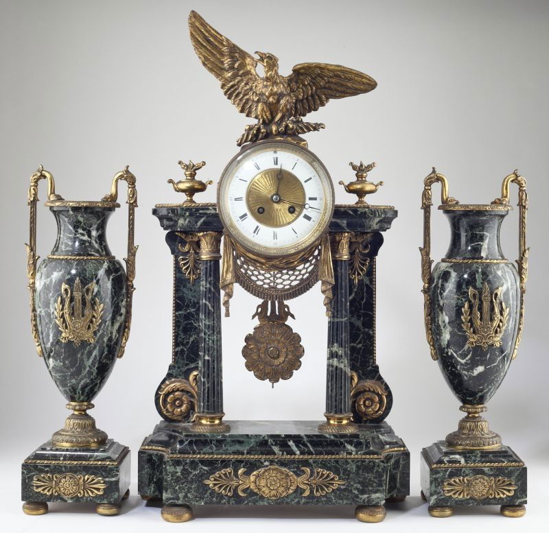 French Empire Mantel Clock Garniture Set: French Empire Mantel Clock Garniture Set 19th century, green marble with ormolu mounts; the cylindrical clock is set over a pierced swag into a portico with four columns, unmarked brass time and strik