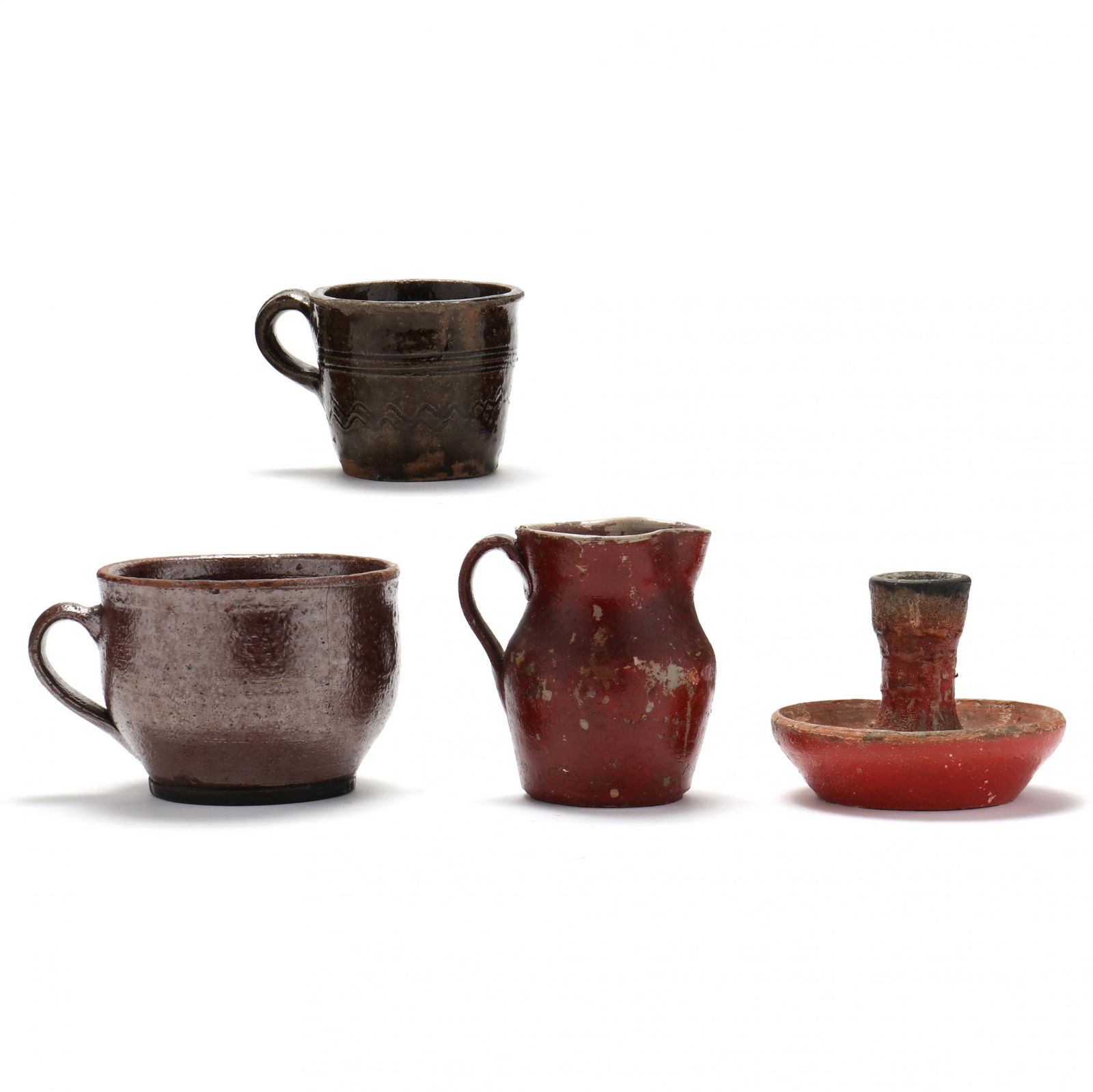Four Early NC Pottery Table Accessories: Four Early NC Pottery Table Accessoriesearly 19th century, a red glazed earthenware chamberstick (4 x 4 in.) (glaze loss, charring at rim, crazing); a red painted stoneware cream jug (4 1/4 in.) (pain