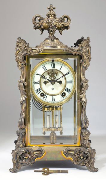 Ansonia Crystal Regulator Clock, circa 1900: Ansonia Crystal Regulator Clock, circa 1900 in the French Neo-Classical style with gilt metal ormolu mounts and floral strewn urn at top. 15 x 7 x 6 in.