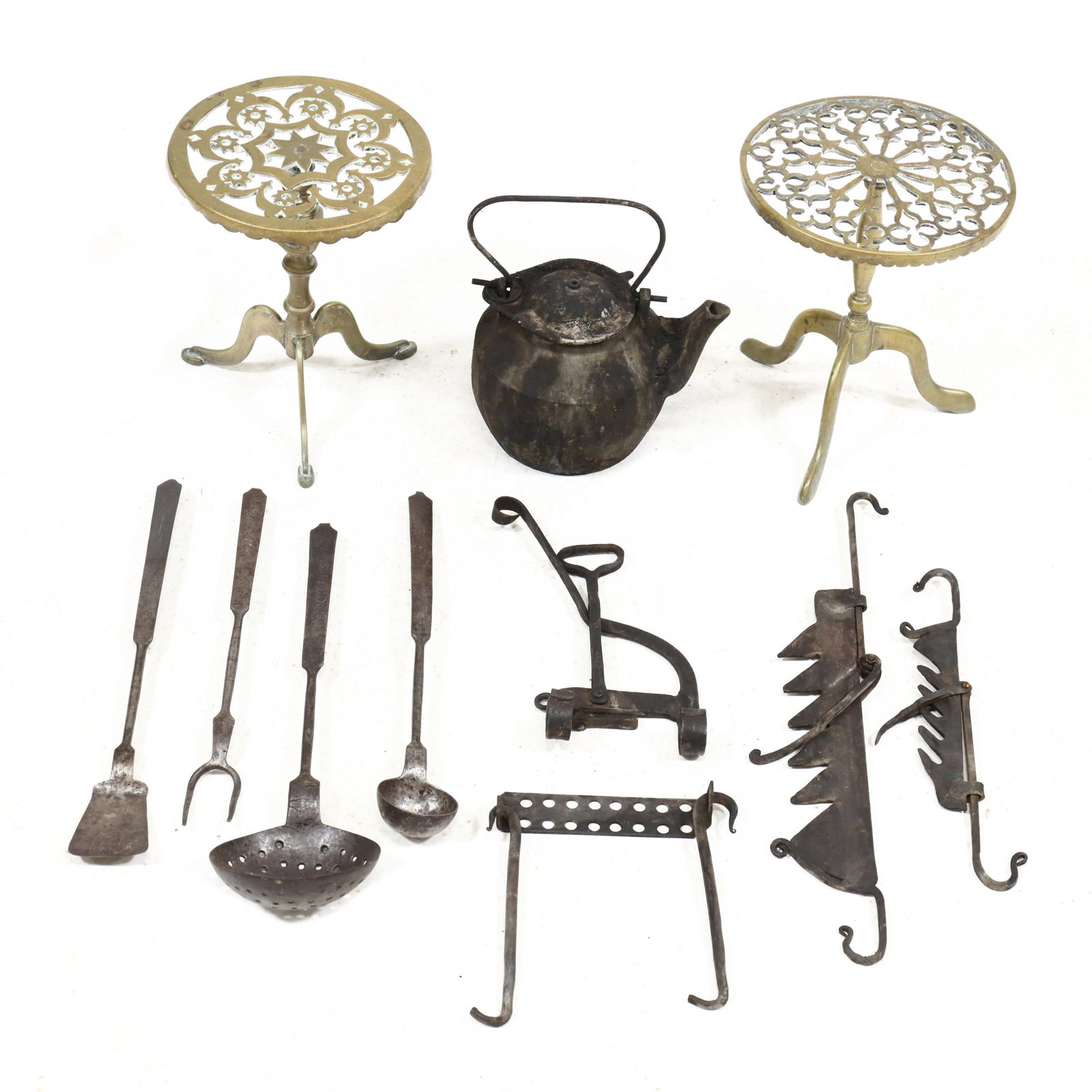 Group of Antique Hearth Accessories: Group of Antique Hearth Accessories19th and early 20th century, including two pierced brass trivet stands with tripod bases, a lidded iron kettle, two trammels and accessories and four wrought steel c