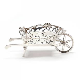 An Edwardian Silver Wheelbarrow, Mark of William Comyns & Sons: An Edwardian Silver Wheelbarrow, Mark of William Comyns & SonsLondon (1908) hallmarks, pattern number A175, reticulated foliate form with floral motifs to rim and functional wheel, without a monogram.