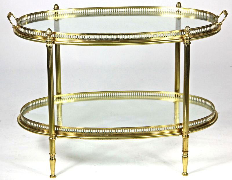 Regency Style Brass Tea Table: Regency Style Brass Tea Table20th century, oval form, two tier with glass inserts, applied handles, four reeded legs with pineapple finials.20.5 x 30 x 17.5 in.