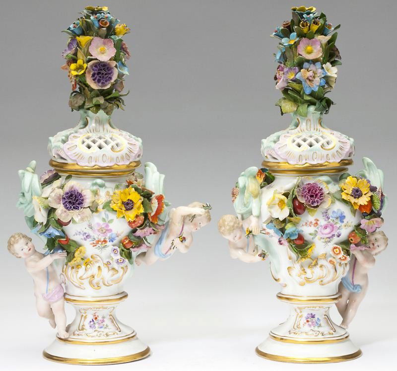Pair of Meissen Lidded Urns: Pair of Meissen Lidded Urnshand-painted porcelain flower and fruit encrusted urns each with two putti, the fitted reticulated lid supports an elaborate floral finial. Meissen pommel mark under glaze o