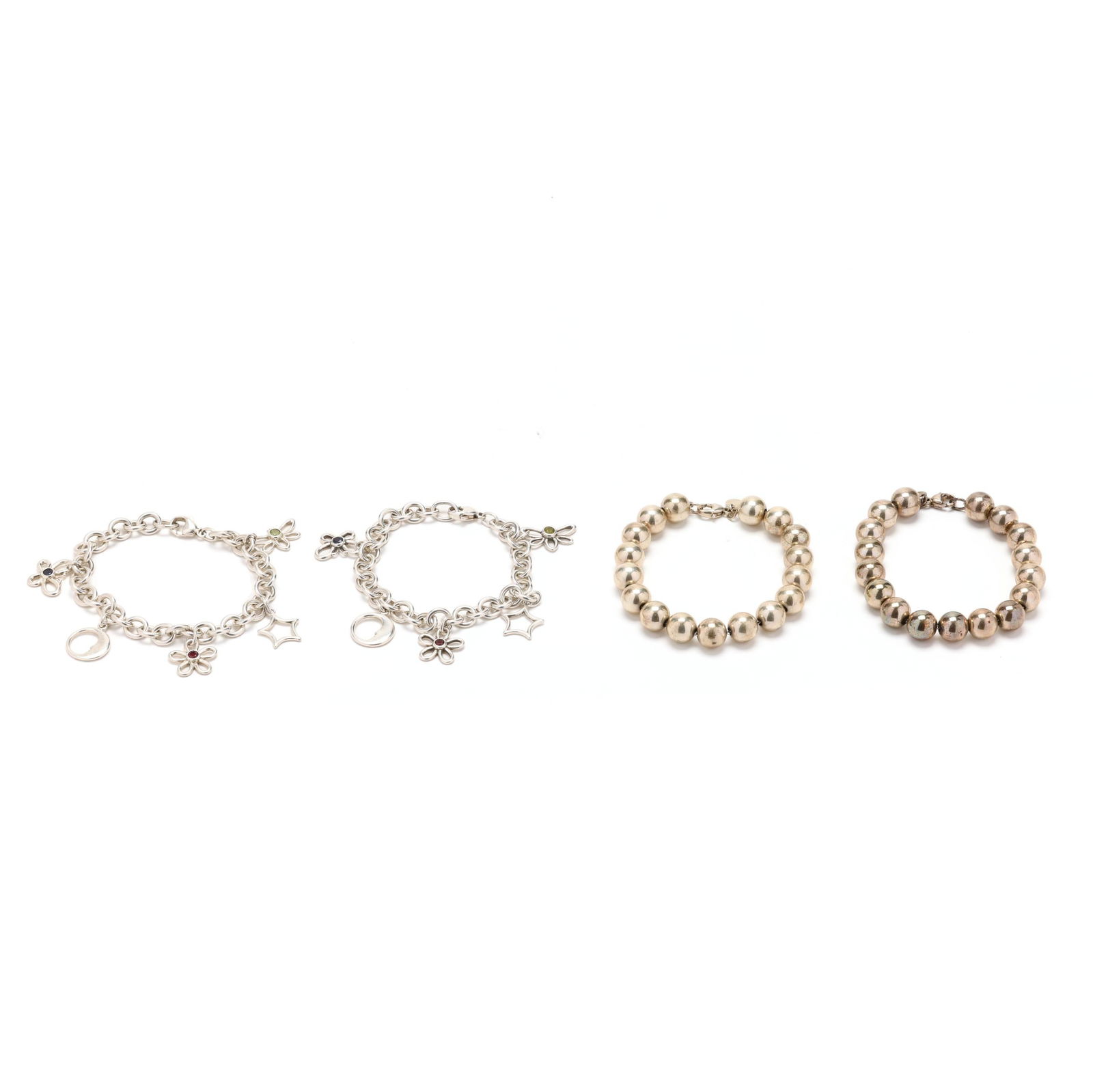 Set of Two Silver Charm Bracelets and Two Silver Beaded Bracelets, Tiffany & Co.: Set of Two Silver Charm Bracelets and Two Silver Beaded Bracelets, Tiffany & Co.to include: two cable chain bracelets suspending five charms to include: a dragon fly charm set with a green stone (.75