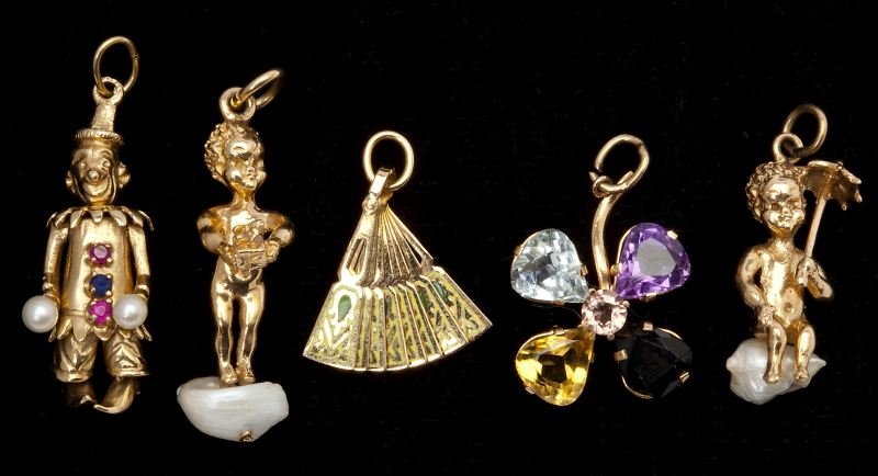 Five Gold Charms: Five Gold Charms the first in an opening fan motif enhanced with green enamel decoration (tests 18KT), the second designed as a gem set four petal flower (stamped 18KT), the third a whimsical jester w