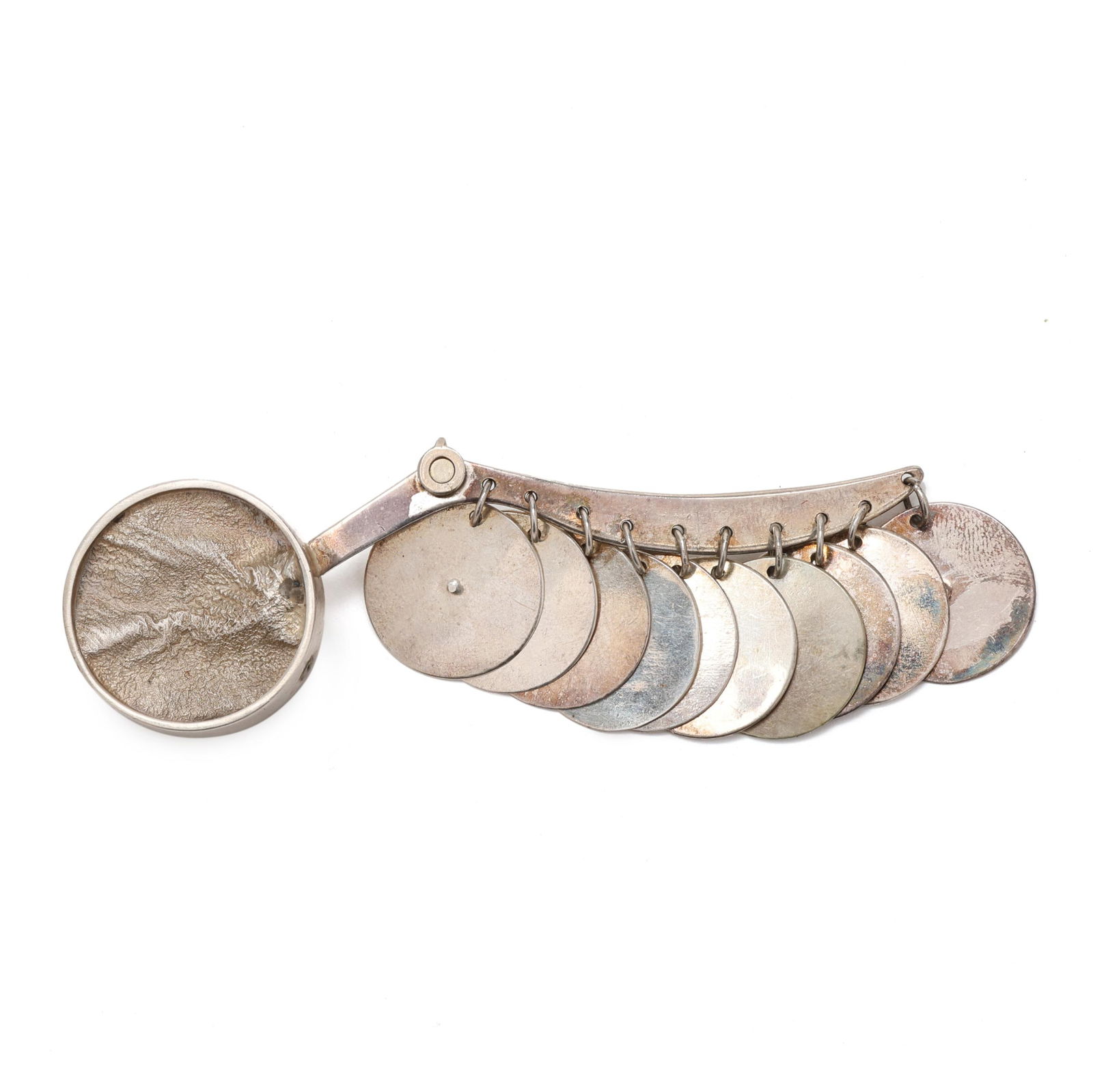 Silver Kinetic Brooch, Mary Ann Scherr: Silver Kinetic Brooch, Mary Ann Scherrcircular inset medallion with the artist's signature reticulation work, shaped arm with circular silver dangles, completed with a pin back, appears unsigned. 1.25
