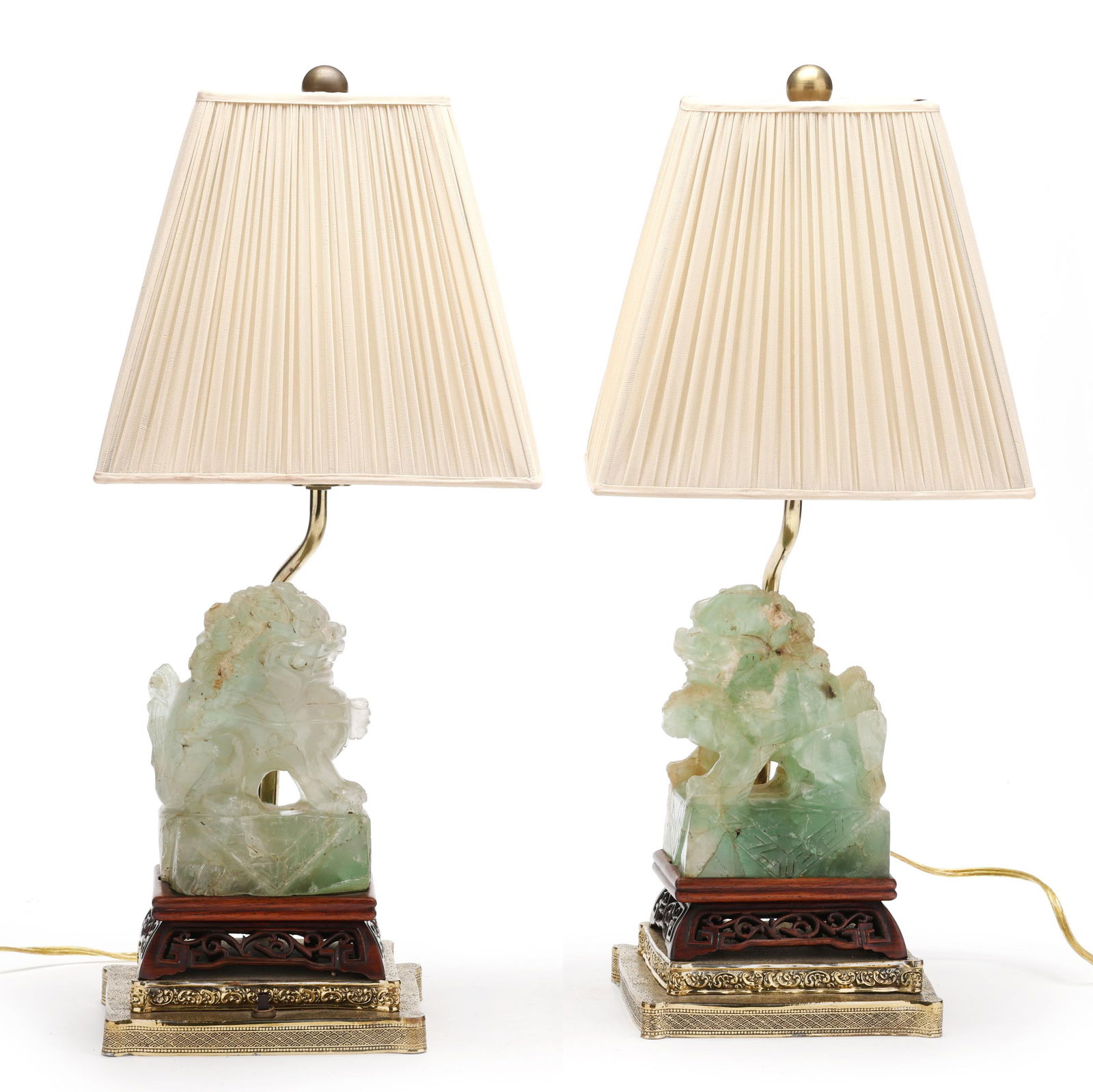 A Pair of Chinese Carved Green Quartz Foo Lion Lamps: A Pair of Chinese Carved Green Quartz Foo Lion Lampslate 19th or early 20th century, celadon green quartz carved foo lions in profile, they are fitted on carved wood bases set into metal stands as lam