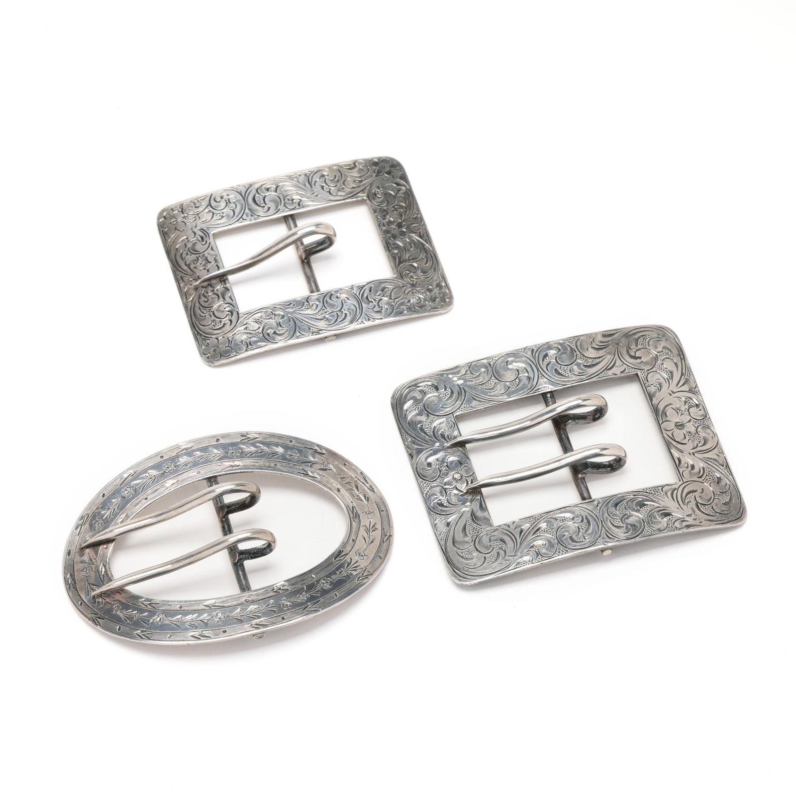 Three Antique Silver Belt Buckles: Three Antique Silver Belt Buckles to include: a rectangular double prong belt buckle with scrolled foliate and floral engravings, with monogram to reverse, stamped Sterling (2 3/8 x 2 7/8 in.; 1.25