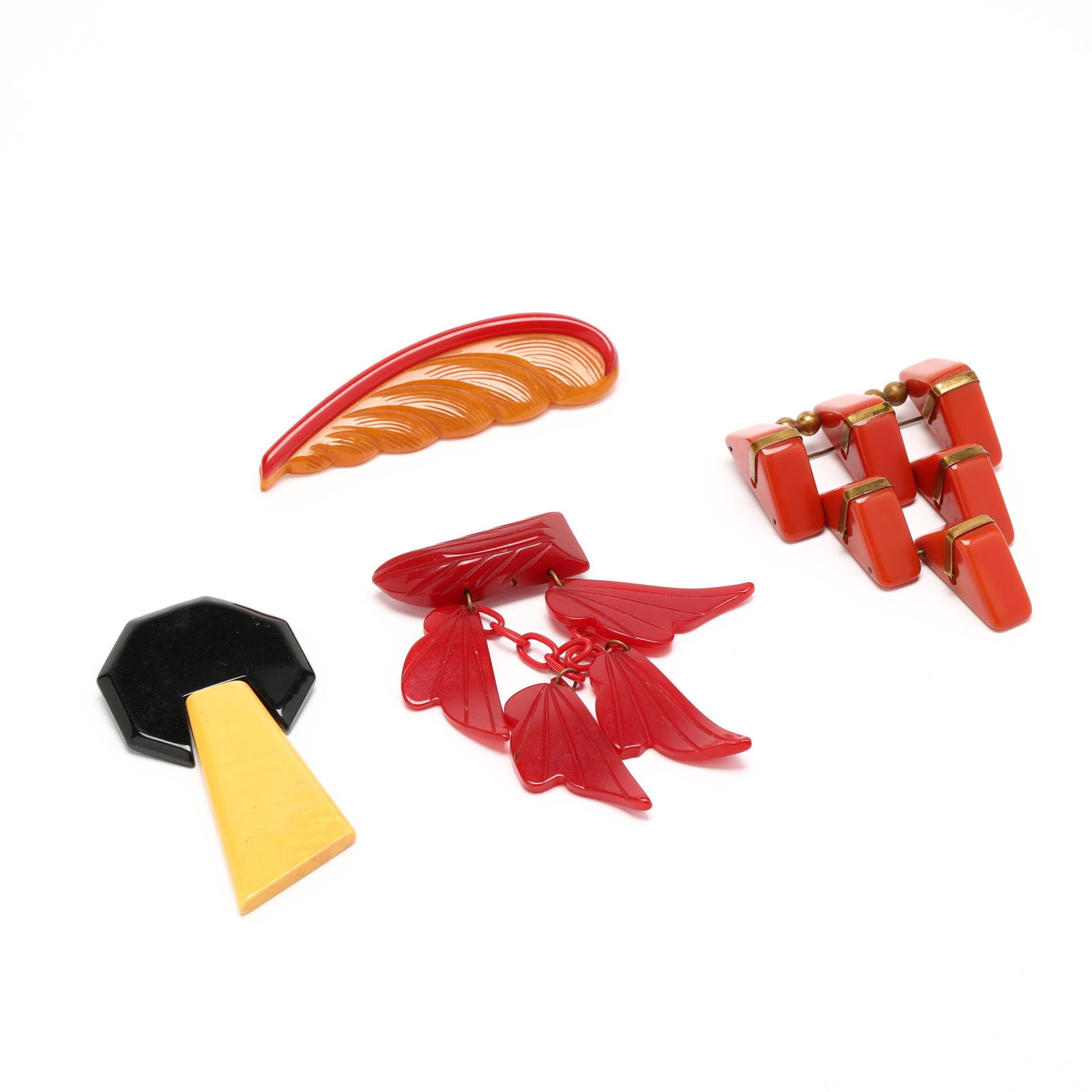 Four Vintage Bakelite Brooches: Four Vintage Bakelite Brooches to include: a brooch in triangular form with articulated elements, brass accents, completed with a single locking pin stem (3 3/8 x 2.5 in.); a yellow and red feather
