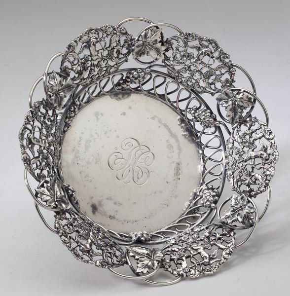 Theodore B. Starr Sterling Wine Bottle Coaster: Theodore B. Starr Sterling Wine Bottle Coasterin the Regency style with reticulated basket featuring grapevine motif and cupid vignettes, raised on four scrolled feet, monogrammed "TC," marked sterlin