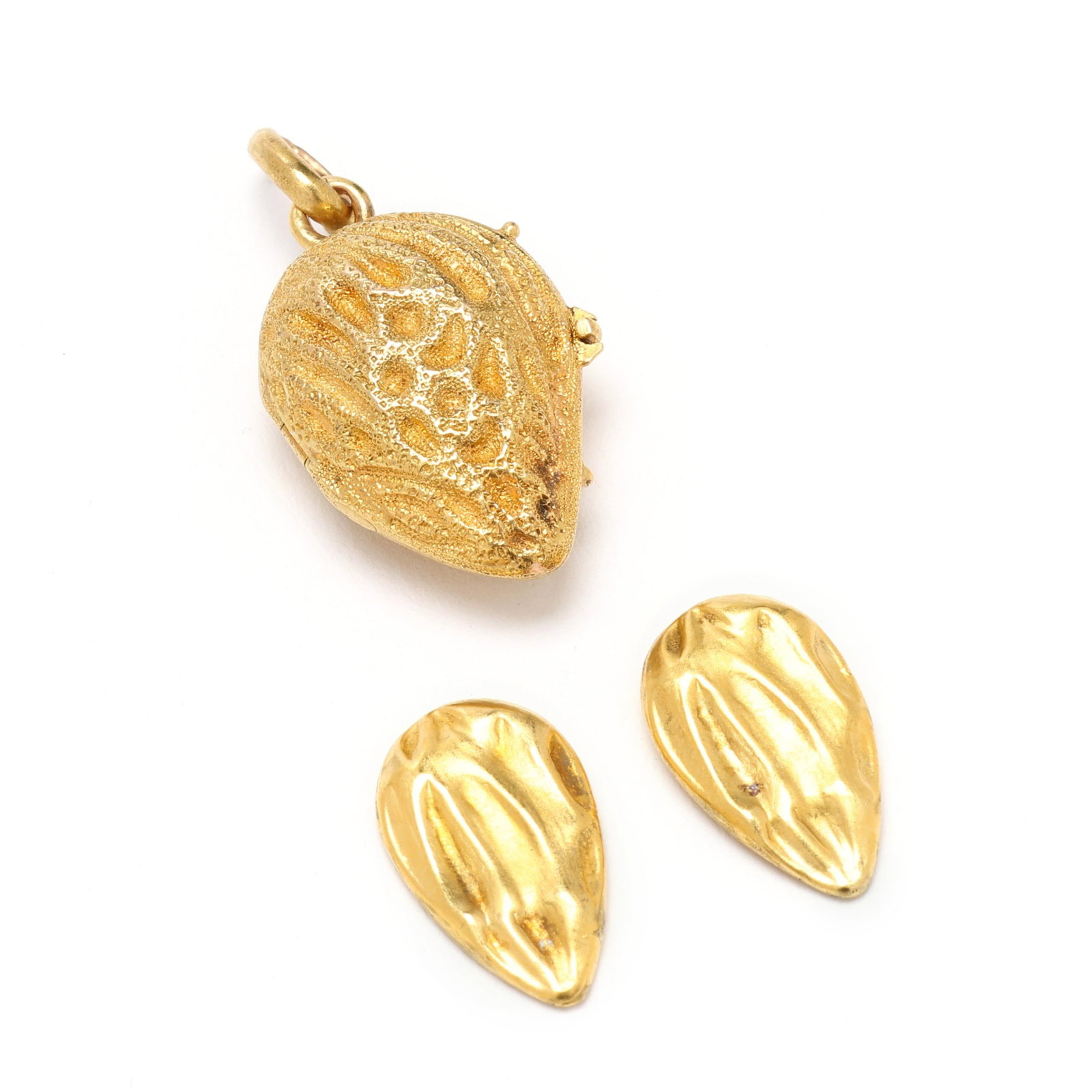 Antique Gold Almond Motif Locket Charm: Antique Gold Almond Motif Locket Charm the textured gold charm in an almond motif, opening to two almond halves, completed with a clasp and bail, stamped with a mark, testing 14KT 1 3/16 x .5 in. 2.1 