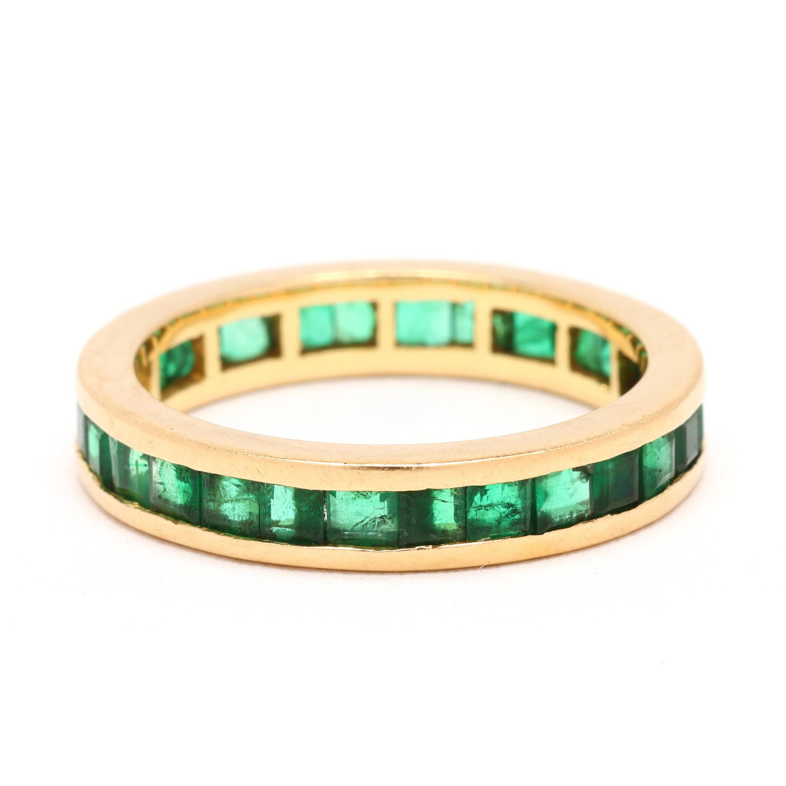 Gold and Emerald Eternity Band: Gold and Emerald Eternity Band the gold eternity band channel set with square cut emeralds weighing approximately 2.25 total carats, stamped 750. 4mm; Ring size 7 2.7 dwt. From a Private Williamsburg,