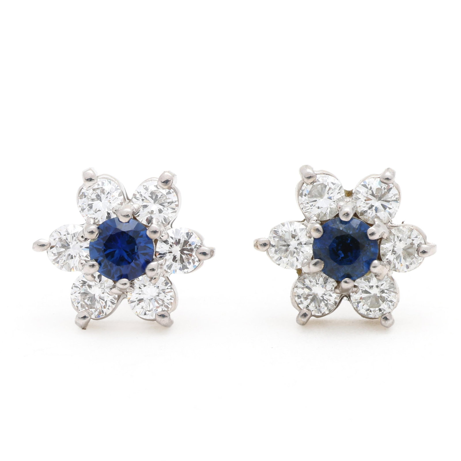 White Gold, Sapphire, and Diamond Flower Motif Earrings: White Gold, Sapphire, and Diamond Flower Motif Earrings in a flower motif, centered on a round cut sapphire within a full cut round diamond surround weighing approximately .50 total carat (I-J color, 