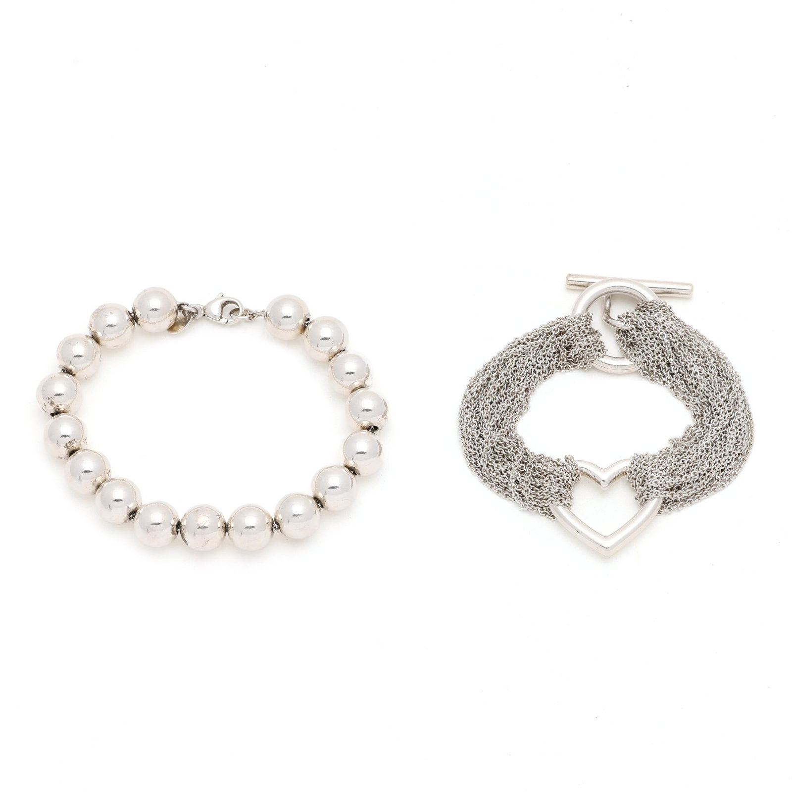 Two Silver Bracelets, Tiffany & Co.: Two Silver Bracelets, Tiffany & Co. to include: a multi-strand bracelet with a central heart element, completed with a toggle clasp, signed and stamped 925 (21mm x 7 in.); and a silver chain strung