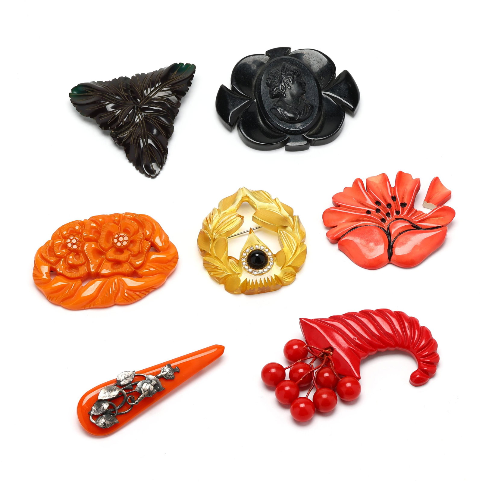 Seven Bakelite Brooches: Seven Bakelite Brooches to include: a red brooch in the form of a cornucopia suspending grapes, completed with a locking pin stem (2.25 x 3 in.); a translucent yellow brooch in the form of a laurel