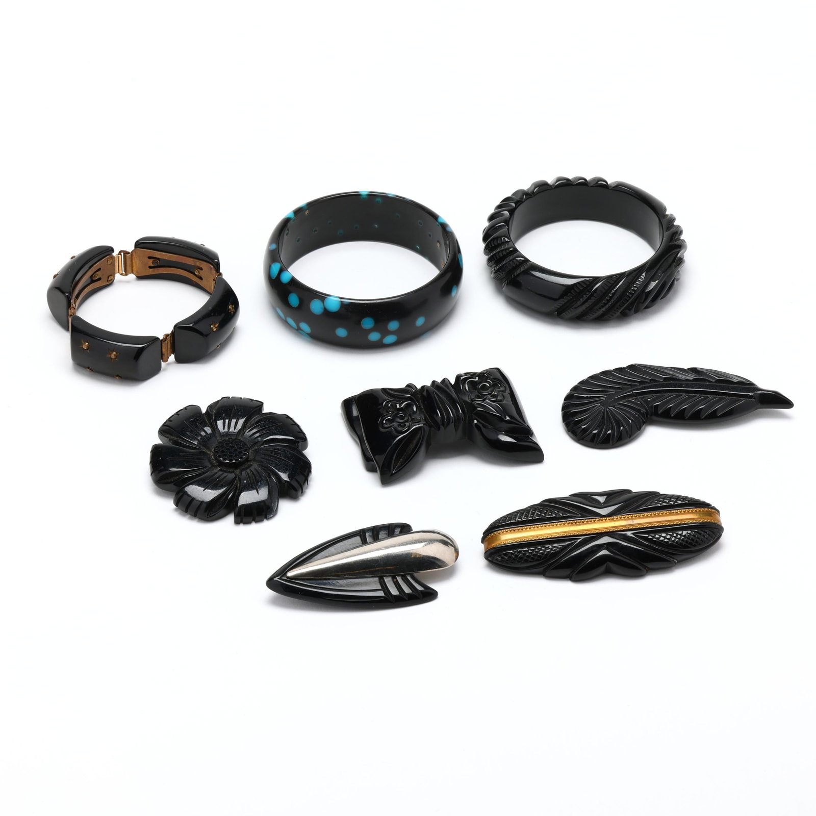 Group of Seven Vintage Composition Jewelry Items: Group of Seven Vintage Composition Jewelry Items to include: a carved black bangle in floral motif (.75 x 7.5 in.); a black bangle with blue spots (1 x 8.25 in.); a black bow brooch with floral design
