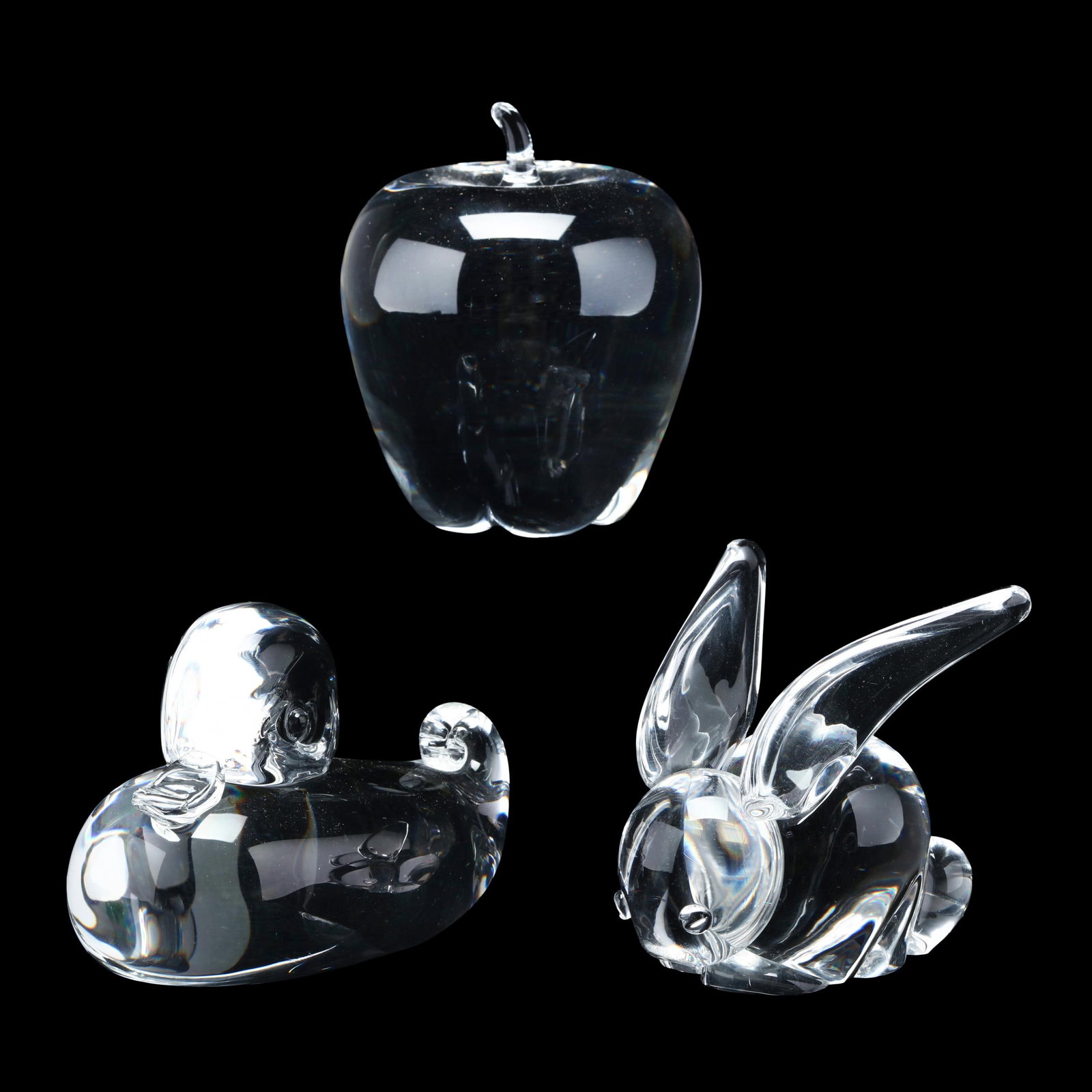 Steuben, Duckling, Rabbit, and Apple Crystal Paperweights: Steuben, Duckling, Rabbit, and Apple Crystal Paperweights Mid-century, clear glass sitting duckling figurine number #8009 by Lloyd Atkins (3.5 x 4.5 in.); clear glass apple designed in 1940 by Angus
