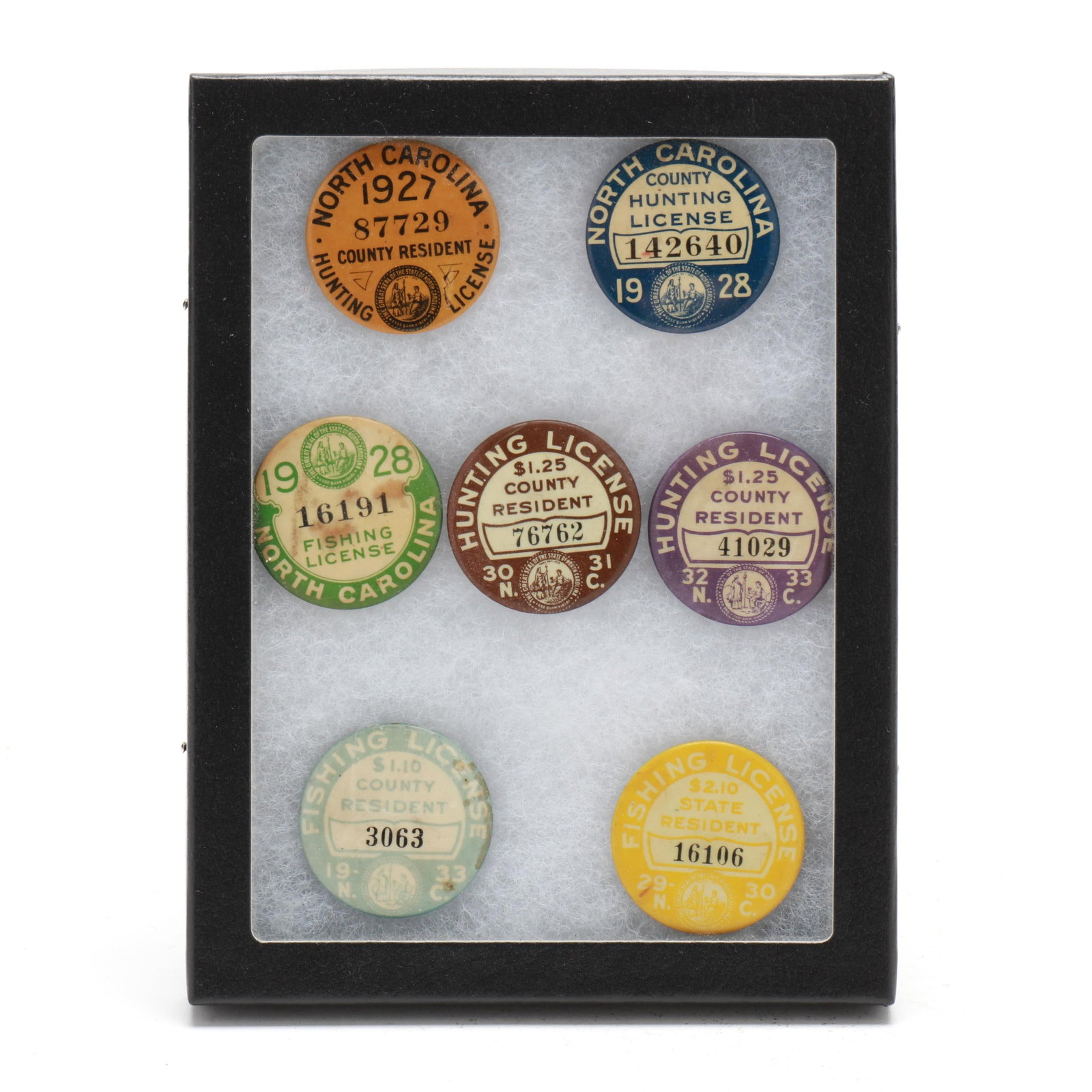 Six Early North Carolina Hunting and Fishing License Pins: Six Early North Carolina Hunting and Fishing License Pins Printed pinback metal badges in display case. Case 8.5 in. x 6.5 x 1 Most metal hunting badges ended in 1941 when the government needed to sav