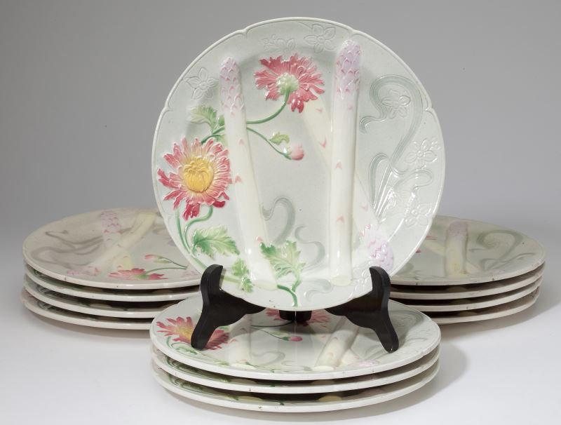 Set of (12) French Majolica Plates by St. Clement: Set of (12) French Majolica Plates by St. Clementcirca 1890, each decorated with raised asparagus spears and peonies against a cream ground with Art Nouveau influenced ribbons and flowers.10.25 in. di