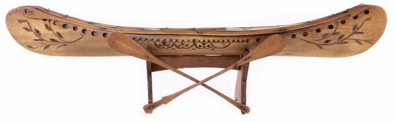 Early Miniature Wooden Canoe Model: Early Miniature Wooden Canoe Model decorated on one side with carved geometric and floral motifs below an arrow-form gunwhale, the interior covered with felt and having a kayak-style single seat, the 
