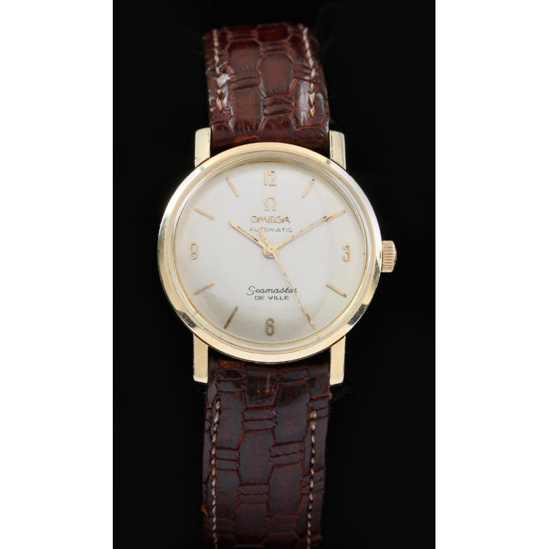 Vintage 14KT Seamaster DeVille Watch, Omega: the round gold case with champagne dial with applied gold baton hour markers and signed "Omega / Automatic / Seamaster /Deville" and completed with brown leather strap band, case stamped 14KT. Case 31