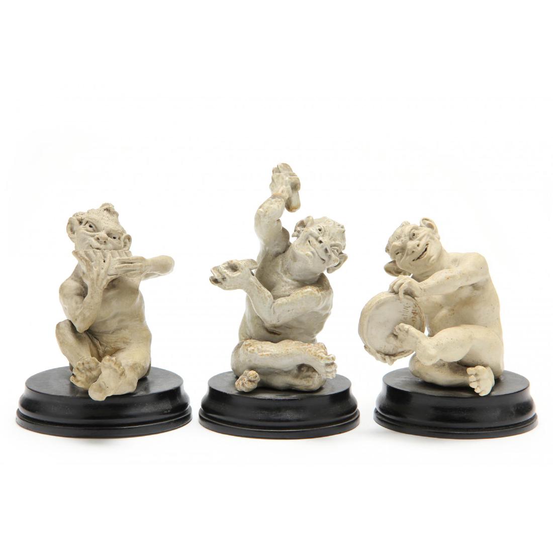 Three Martin Brothers Stoneware Grotesques: England, 1890s, consisting of seated musical imps mounted to their original circular ebonized wooden bases. A pipe player and the clacker player are both incised with "Martin Bros. London," while the
