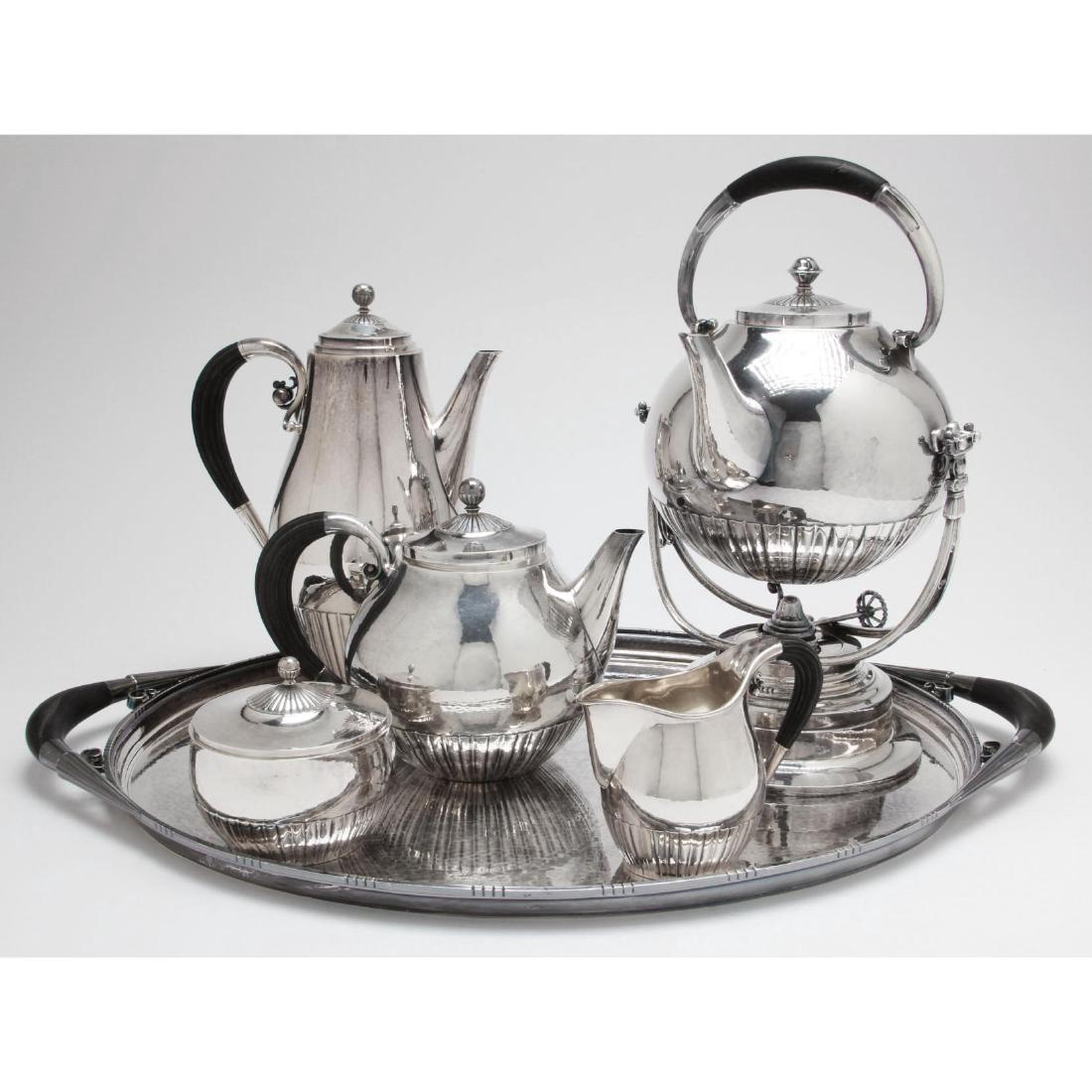 Georg Jensen Sterling Silver Tea & Coffee Service: (6) pieces in the "Cosmos" pattern including a coffee pot (10.5 in.), teapot, kettle on stand, sugar bowl with cover, creamer, and double handled waiter (251C). The service a design by Johan Rohde, ea