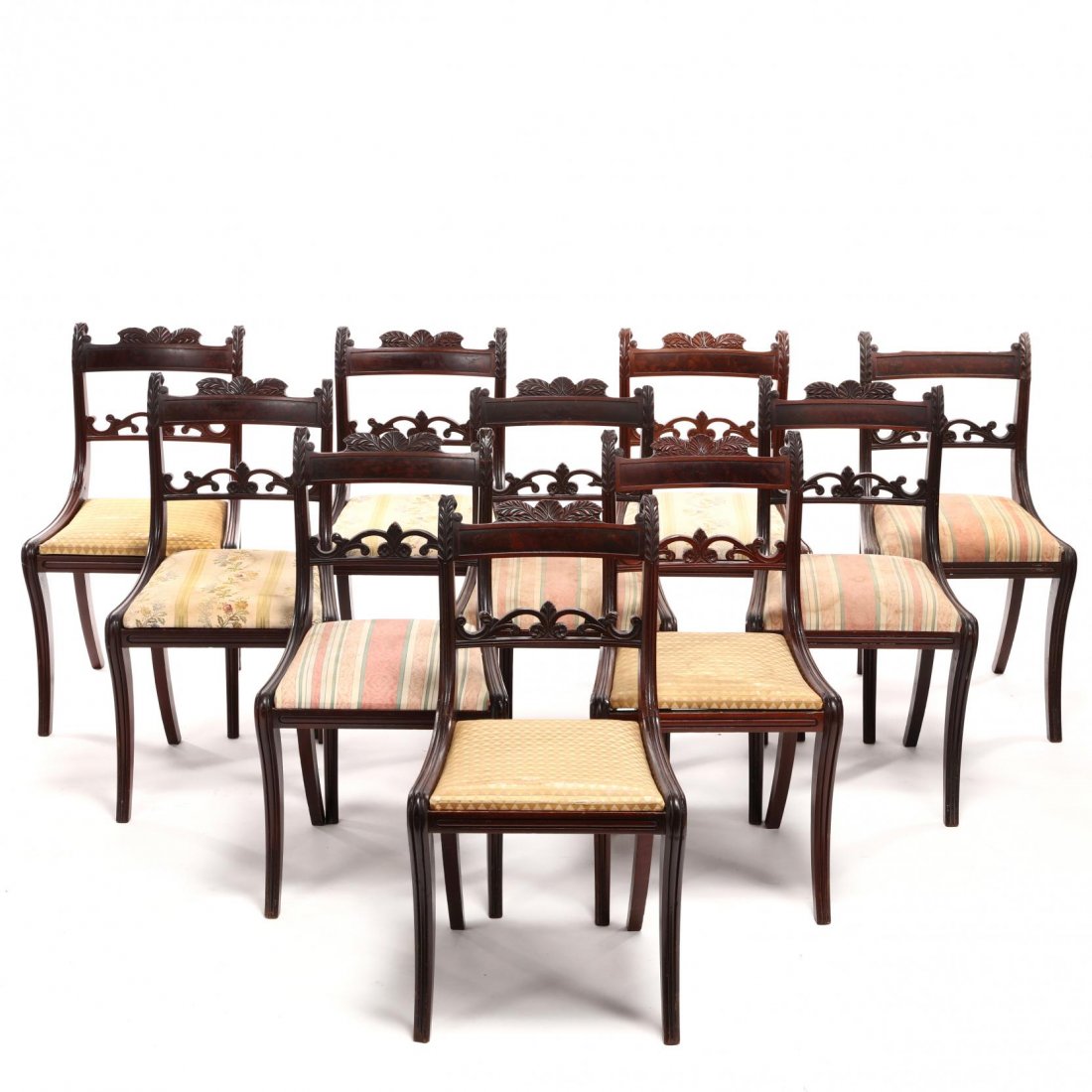 A Set of Ten Classical Carved Dining Chairs: attributed to Duncan Phyfe (1770-1854), New York, 1810-1820, mahogany and mahogany veneer, ash secondary, the crest rail is centered with a figured mahogany veneered panel below a trio of carved leave
