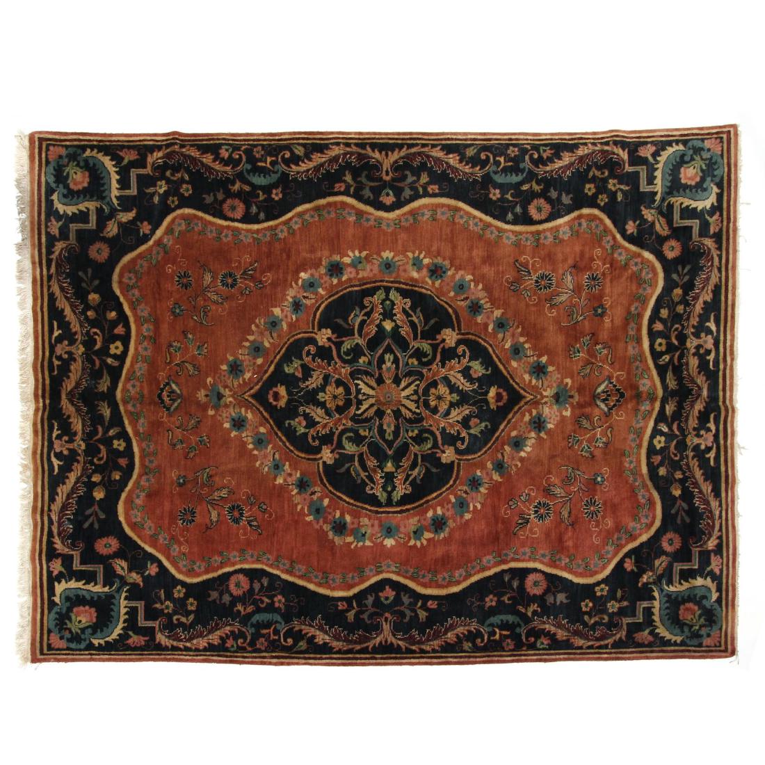 Handwoven Rug: the rust field with center dark blue floral and vine medallion and field with floral spray and rosette design elements with dark blue ground. 7 ft. 10 in. x 9 ft. 8 in.