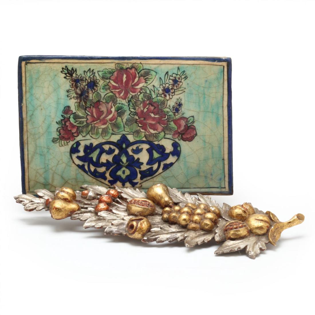 Two Antique Decorative Wall Plaques: the first a silvered and gilt carved wood plaque featuring fruit and foliate motif (19 x 5.5 in.) (some minor flaking to surface); the second an antique ceramic tile, likely Spanish, featuring a vase