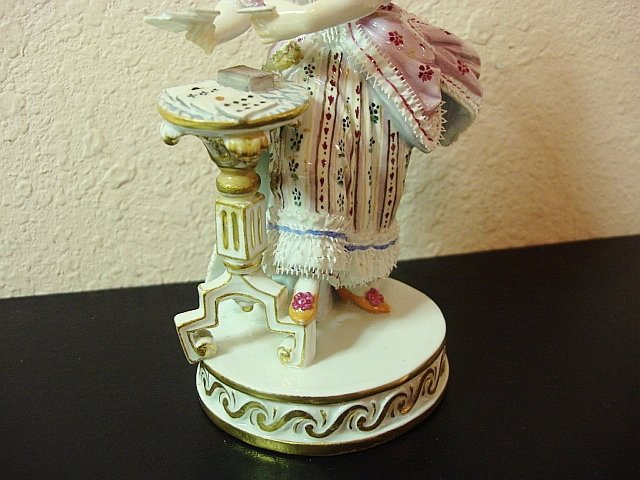 A Meissen porcelain figure of a lady by a table