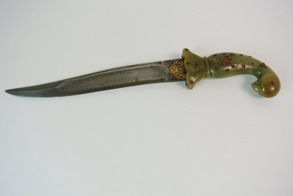 A MUGHUL STYLE JADE DAGGER: A 19th century Mughal style dagger, very finely gold inlaid steel blade, inset with semi precious stones.Estimate $1.500-2.000