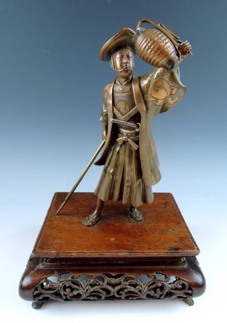 MEIJI PERIOD JAPANESE BRONZE: Wonderful BRONZE JAPANESE SCULPTURE - BronzeFigure of a Yuki Clan Watchman holding lantern aloft, wearing helmet & sword, carrying spear. 19th C., with the Samurai clan mon or crest on his robe. Mount