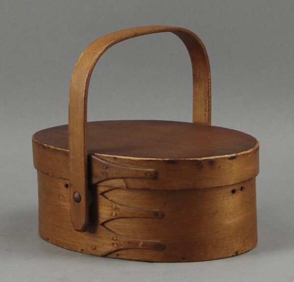 Shaker 19C. Sewing Carrier Box with Swing Handle: Shaker 19C Oval Handled Sewing Carrier The oval handled carrier has three fingers on the bottom and one on the lid. Old vanish finish, glue residue from missing silk interior and a chip on one end of 