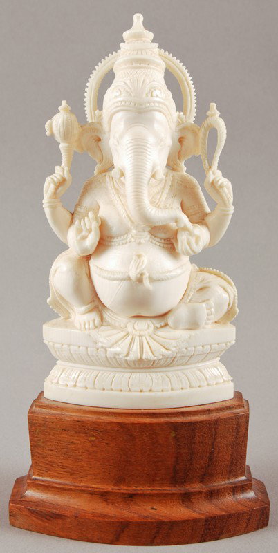 Carved Ivory Elephant God Ganesh India: Carved Ivory Elephant God Ganesh India is mounted on a conforming wooden base. The tip of one tusk is chipped. The ivory measures 5" high with the base it measures 7" high.