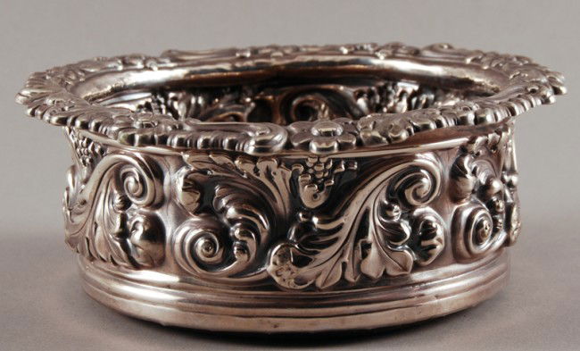 English Sterling Silver 19C Repousse Wine Coaster: English Sterling Silver 19C Repousse Wine Coaster has a worn hallmark, maker unknown. Turned oak insert. Measures 2 1/2" h. 6 1/2" d. Weight including insert is 12 troy ounces. In good condition with