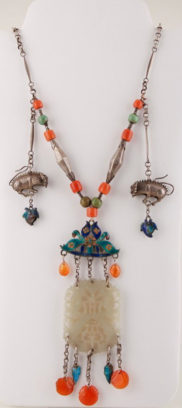 Chinese Silver Enamel Carnelian Jade Necklace: Chinese Silver Enamel & Jade Necklace. The necklace has coral, turquoise and carnelian beads. Enameled leaves wit two silver foo dogs the pendant is carved jade. In good condition. The chain is 25" lo