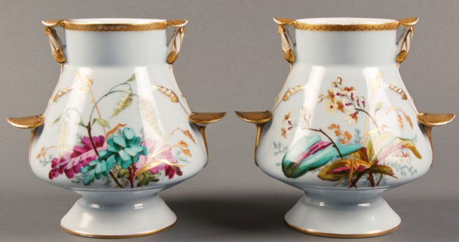 Pair of Old Paris Gilt 19C Porcelain Floral Urns: Pair of Old Paris 19C porcelain vases. The vases or urns are decorated with hand painted flowers accented with gilt lily pad form tab handles. They are in good condition. The tips of two of the tab ha